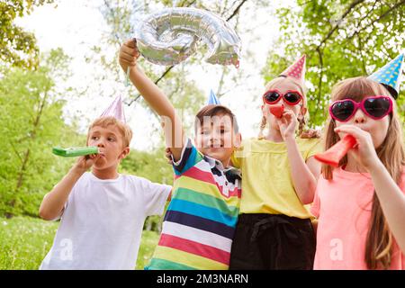 Des enfants multiraciaux joyeux fêtant leur anniversaire avec des éruptions dans le parc pendant les vacances d'été Banque D'Images