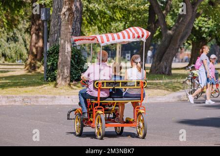 30 juillet 2022, Cologne, Allemagne: Famille ayant un tour de détente sur un vélo à quatre roues ou quadcycle dans le parc Banque D'Images