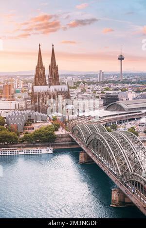 Cologne vue aérienne verticale avec les trains se déplace sur un pont au-dessus du Rhin sur lequel se trouvent les barges de cargaison et les navires à passagers. Majestueuse cathédrale de Cologne Banque D'Images