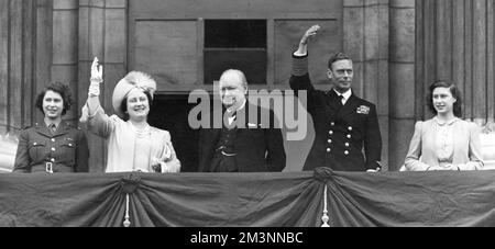 Le roi George VI, la reine Elizabeth (plus tard la reine mère) avec leurs filles, la princesse Elizabeth (plus tard la reine Elizabeth II) en uniforme ATS et la princesse Margaret Rose, et le premier ministre, Winston Churchill, sur le balcon du Palais de Buckingham, qui agite à la foule le jour du VE, 8 mai 1945. Date: 1945 Banque D'Images