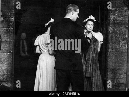 Photographie prise à l'abbaye de Romsey, dans le Hampshire, lorsque le lieutenant Philip Mountbatten a été l'huissier du mariage de l'honorable Patricia Mountbatten au capitaine Lord Brabourne, alors que les deux Princesses étaient des bridesmides. Le lieutenant Philip Mountbatten rencontrait la princesse Elizabeth et la princesse Margaret à leur arrivée, quand il les a aidés avec leur manteau. La princesse Elizabeth est sur la droite. 19th juillet 1947 1947 Banque D'Images