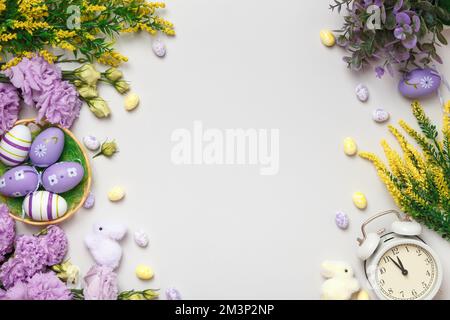 Composition de Pâques. Œufs de fleurs violettes et jaunes dans un réveil à panier. Banque D'Images