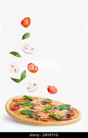 Pizza aux champignons, tomates, fromage et basilic sur fond blanc. Chute d'ingrédients. La lévitation Banque D'Images