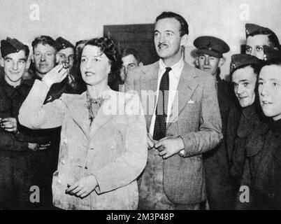 Mme Ronald Tree et l'acteur David Niven à un concours de fléchettes dans une cantine. Nancy Lancaster (1897 - 1994), née Perkins, était une femme influente de cuisine américaine, décoratrice d'intérieur et designer de jardin. Elle épousa Ronald Tree en 1920, déménaga en Grande-Bretagne en 1927; le couple divorça en 1947 et elle épousa Claude Lancaster en 1948. Elle a été associée au style de maison de pays anglais. Date: 1939 Banque D'Images