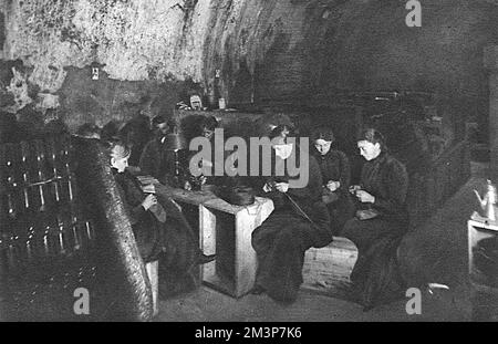 Les femmes françaises trient le « confort » pour les soldats dans une cave à vin sombre, faiblement éclairée par des bougies à Reims, un refuge contre le feu de coquillages dans la ville fréquemment bombardée. Date: 1914 Banque D'Images