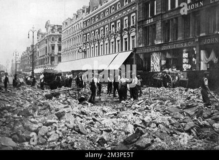 Après qu'un certain nombre de voies de circulation londoniennes aient été sérieusement négligées pendant la première Guerre mondiale, de nombreuses routes et rues célèbres ont été réparées par des ouvriers en 1919. Oxford Street est une photo ici, avec la route - entièrement creusée - rappelle une scène après un raid. Le grand magasin John Lewis se trouve sur la droite. 1919 Banque D'Images