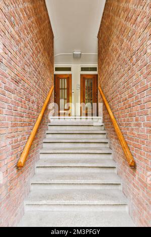 quelques escaliers menant à la porte d'entrée sur un bâtiment en brique avec des rampes en bois et des mains courantes en bois Banque D'Images