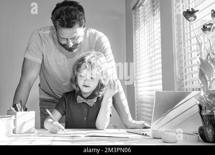 père barbu écrivant des devoirs à l'école avec son fils enfant en classe, parent Banque D'Images