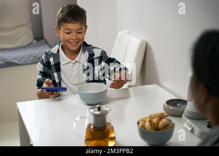 Beau enfant prenant son petit déjeuner dans la cuisine Banque D'Images