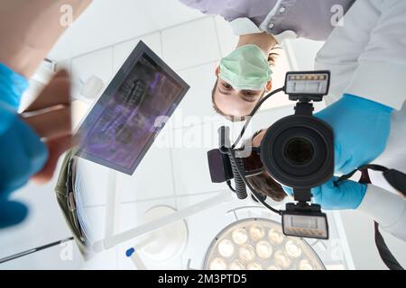 Un dentiste qui photographie les dents des clients avec un appareil photo numérique Banque D'Images