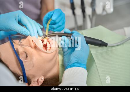 Dentiste effectuant une procédure de blanchiment des dents sur le client assisté par une infirmière Banque D'Images