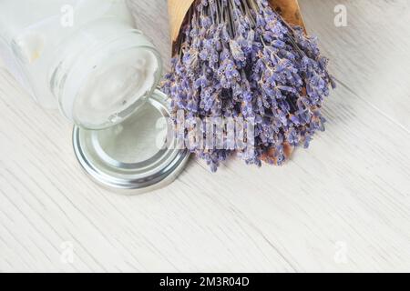 Pot de crème à la main et fleurs de lavande séchées sur fond clair. Cosmétiques holistiques. Banque D'Images