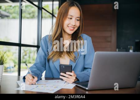 femme assise dans des cafés avec un smartphone mobile, elle écrit une note sur le graphique de la paperasse Banque D'Images
