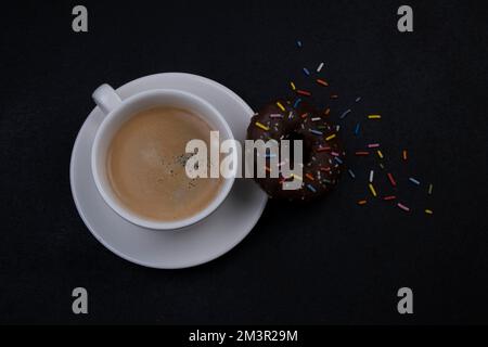 prend un café avec un beignet de chocolat et des asperges multicolores sur fond noir vue du dessus. Haute qualité Banque D'Images