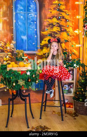 Fille dans un costume du nouvel an à une table avec des mandarines Banque D'Images