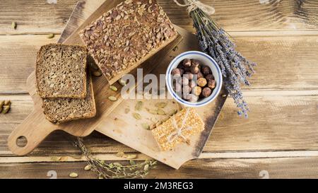 Vue de dessus bol à pain aux grains entiers et noisettes avec planche à découper à barres protéinées. Résolution et superbe photo de haute qualité Banque D'Images