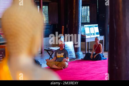 Chiang Mai, Thaïlande, 16/12/2022, des touristes étrangers assistent à une séance de prière pour bénir la princesse thaï Bajrakitiyabha pour sa récupération lors de la raies bouddhistes thaïlandaises à l'intérieur du temple Wat Phan Tao, à Chiang Mai. Le patriarche bouddhiste suprême de Thaïlande a chargé les moines thaïlandais du royaume et de l'étranger de prier pour bénir la princesse Bajrakitiyabha. La princesse thaïlandaise a été admise à l'hôpital mémorial du Roi Chulalongkorn après qu'elle est tombée inconsciente le soir du 14 décembre 2022 en raison de symptômes cardiaques, a annoncé le Bureau de la maison royale le 15 décembre 2022. Banque D'Images