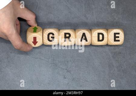 Le symbole de mise à niveau ou de rétrogradation. L'entrepreneur tourne le cube en bois et remplace le mot 'Downgrade' par 'upgrade'. Banque D'Images