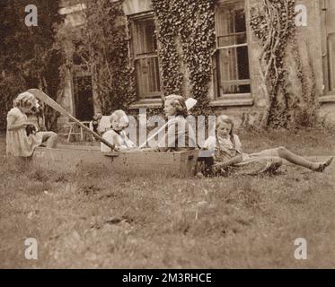 Auteur et dramaturge Daphne du Maurier(1907-1989) et ses enfants Tessa, Flavia et Christian à l'extérieur de leur maison Cornish Menabilly en 1944. Christian pratique son aviron dans un bateau factice. Date: 1944 Banque D'Images