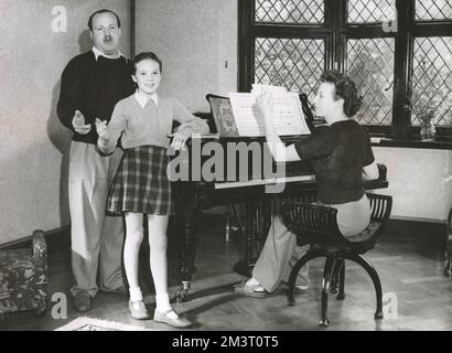 Julie Andrews, âgée de 12 ans, photographiée à la maison avec sa mère Barbara au piano et son beau-père, au moment où elle apparaissait dans Starlight Roof à l'hippodrome de Londres, la revue Robert Nesbitt dans laquelle elle fit ses débuts sur scène en chantant le Mignon Polonnaise, pour un grand succès. Date: 1947 Banque D'Images