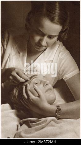 Élimination des cheveux superflus : un mélange chaud de paraffine et d'échellac appliqué sur les sourcils et épluché quelques minutes plus tard. Date: 1933 Banque D'Images