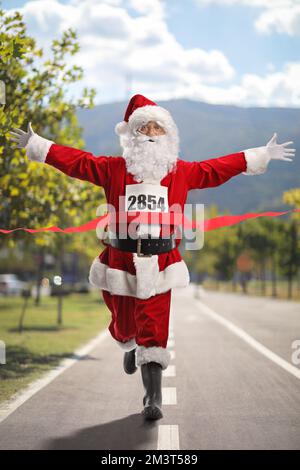 Heureux Père Noël finissant d'abord une course sur une route asphaltée dans la ville Banque D'Images