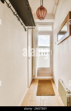 un couloir avec parquet et un luminaire suspendu sur le mur devant la porte de la pièce Banque D'Images