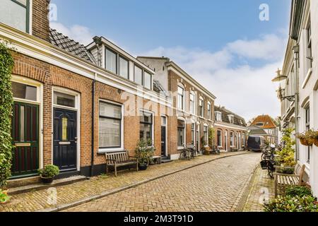 une vieille rue aux pays-bas avec des bâtiments en briques et des plantes vertes de chaque côté, il y a un ciel bleu Banque D'Images