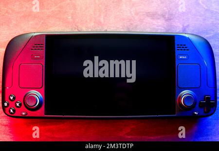 Lublin, Pologne. 16 décembre 2022. Console de jeu de la valve Steam Deck sur table en bois, éclairée par des LED modernes rouges et bleues Banque D'Images