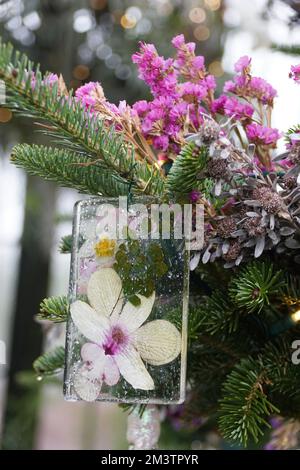 Un arbre décoré d'ornement en fleurs, une fleur d'orchidée blanche et violette pressée entre deux verres Banque D'Images