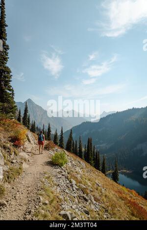 Vertical photo de 30s femme debout sur le sentier avec des buissons, des arbustes et des conifères massifs de haute altitude sur le tr Banque D'Images