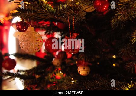 Décoration de l'arbre de Noël avec des cloches rouges dans le style vintage, boules blanches avec ouverture de coupe. Le bokeh lumineux s'allume sur fond vert. Décorati Banque D'Images