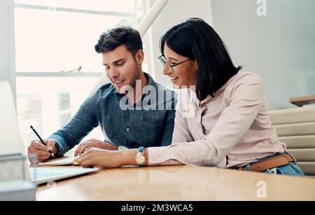 Les idées écrites deviennent réalité. deux jeunes gens d'affaires assis ensemble au bureau et passant par la paperasse. Banque D'Images