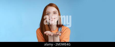 Mignon tendre gentille jeune fille de gingembre donnant tout l'amour vous, tenir quelque chose de palmiers montrant l'appareil photo sourire ravie présente sourire romantique Banque D'Images