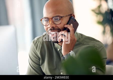 Nous pouvons organiser une réunion dans la semaine. un jeune homme d'affaires parlant sur son téléphone portable tout en étant assis derrière son ordinateur. Banque D'Images