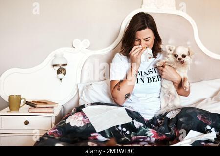 Le temps avec mon chien est juste le genre de confort dont j'ai besoin. une femme assise sur son lit avec son chien tout en souffrant d'un froid à la maison. Banque D'Images