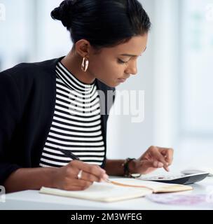 Réduisez vos dépenses afin d'avoir un plus grand profit. une jeune femme d'affaires attirante travaillant ses finances avec une calculatrice et un bloc-notes dans elle Banque D'Images