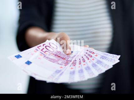 Discussions de trésorerie. une femme d'affaires méconnue tenant une pile d'argent à l'intérieur de son bureau au travail. Banque D'Images