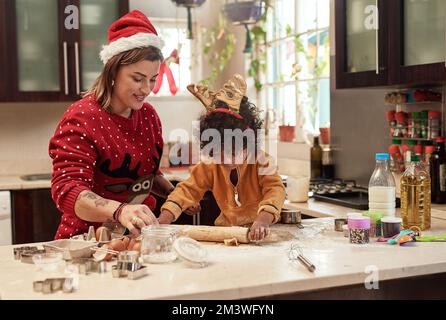 Vous allez vraiment bien. une jeune femme gaie et son fils qui cuisent des biscuits ensemble dans la cuisine pendant les fêtes à la maison. Banque D'Images