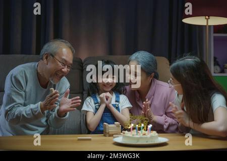 les grands-parents et la mère célèbrent la fête de chant d'anniversaire avec le gâteau de la petite-fille Banque D'Images