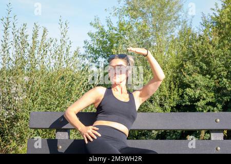 Sports de plein air par temps chaud. Une jeune femme couvre son visage avec sa main du soleil éclatant Banque D'Images