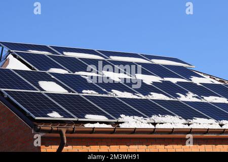 Panneaux solaires couverts de neige, sur le toit du cottage. Énergie verte pour le chauffage en hiver Banque D'Images