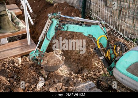Une minipelle creuse une tranchée pour poser les tuyaux. Gros plan d'une pelle hydraulique creusant une tranchée profonde. Une pelle hydraulique creuse une tranchée dans la campagne pour déposer un Banque D'Images