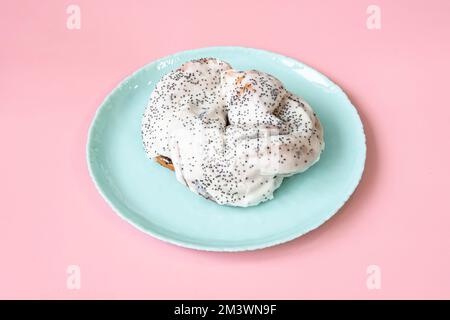 Un petit pain sucré aux graines de pavot dans de la crème blanche sur fond rose Banque D'Images