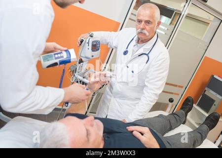 un médecin de sexe masculin teste le diabète d'un homme âgé à l'hôpital Banque D'Images