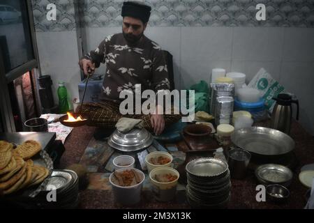 16 décembre 2022, Srinagar, Jammu-et-Cachemire, Inde: Un chef verse de l'huile chaude sur les assiettes contenant Harisa pour servir les clients lors d'une matinée froide sur 16 décembre 2022 à Srinagar, Inde. Harisa est une recette de mouton unique et ancienne préparée pendant les hivers au Cachemire. Il est principalement disponible dans les heures du matin fait de mouton en particulier de mouton (Credit image: © Mubashir Hassan/Pacific Press via ZUMA Press Wire) Banque D'Images