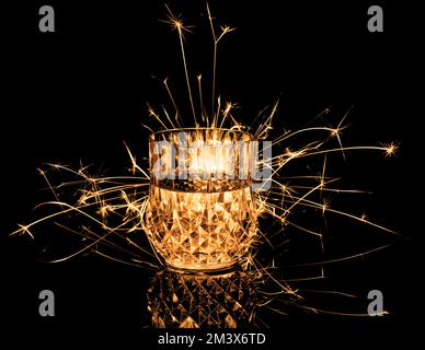 Verre, boire avec un sparkler de fizzy isolé sur fond noir. Banque D'Images