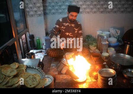 Srinagar, Inde. 16th décembre 2022. Le gérant de magasin verse de l'huile de cuisson chaude sur une assiette contenant un plat à viande, connu localement sous le nom de « Harisa », avant du servir à ses clients à Srinagar, le 16 décembre 2007. Harisa est un repas préféré que Kashmiris mange tôt le matin en hiver dans des magasins spécialement aménagés appelés la fourgonnette Harisa. (Photo de Mubashir Hassan/Pacific Press) crédit: Pacific Press Media production Corp./Alay Live News Banque D'Images
