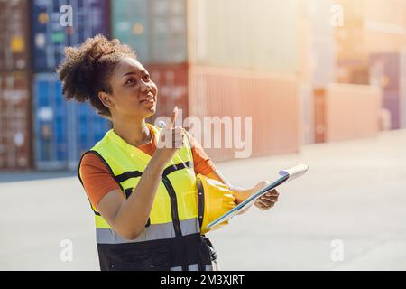 Femme africaine de logistique de cargaison employé de l'industrie heureux de travailler dans les conteneurs de contrôle de chantier naval de port Banque D'Images