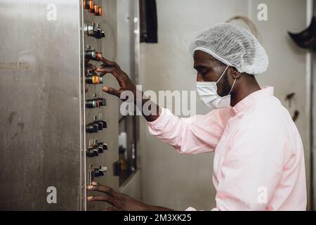 Le personnel d'un travailleur nigérian africain qui travaille contrôle le processus de production de l'usine de produits alimentaires et de boissons Banque D'Images